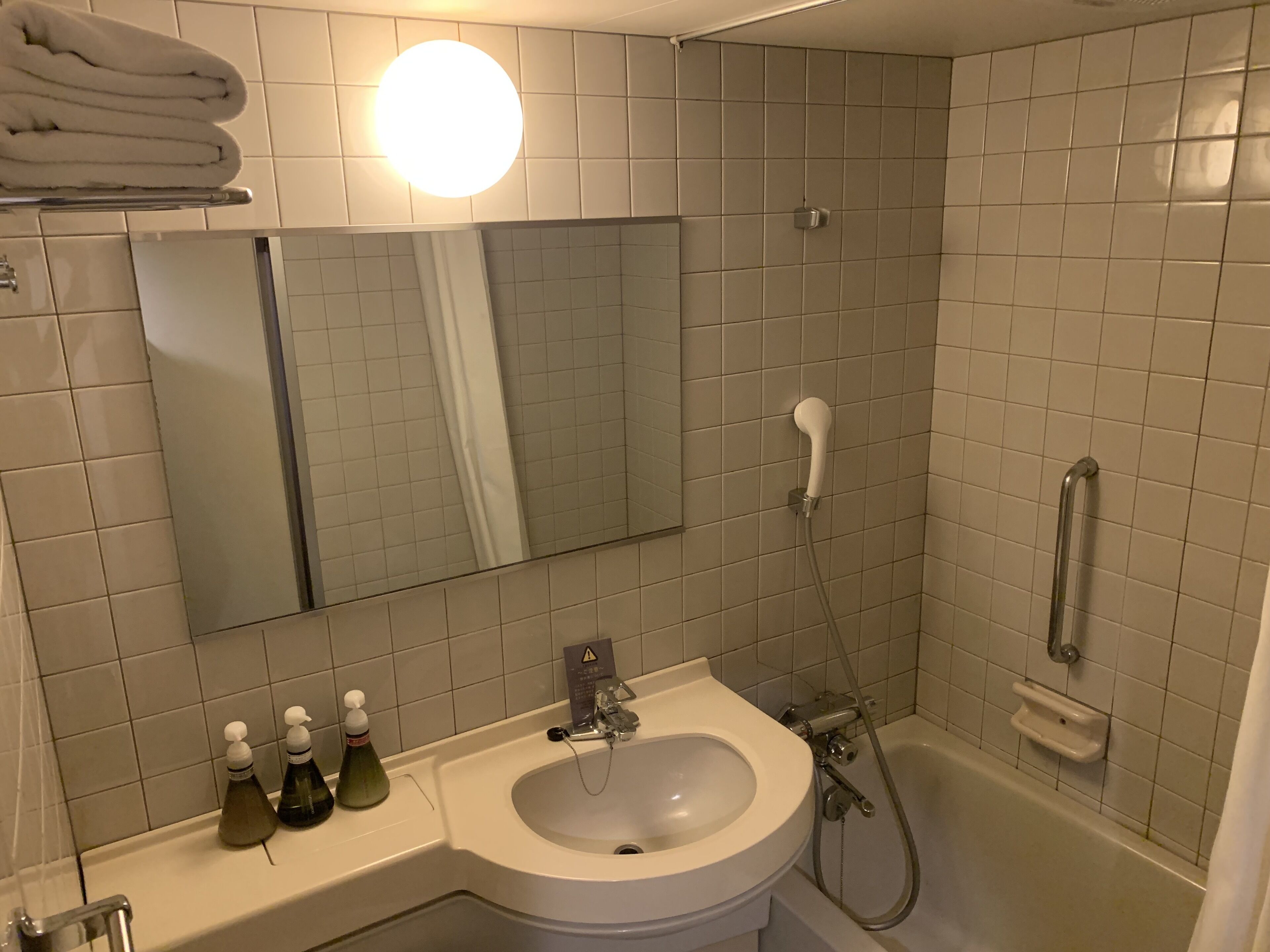 A bathroom with a sink, mirror, towel rack, and a shower.