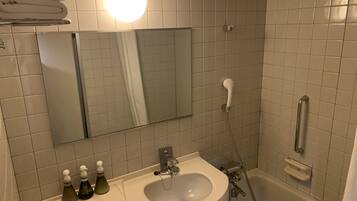 A bathroom with a sink, mirror, towel rack, and a shower.