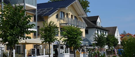 Un hotel de varios pisos con balcones, una zona de estar cubierta al aire libre y un cielo despejado.