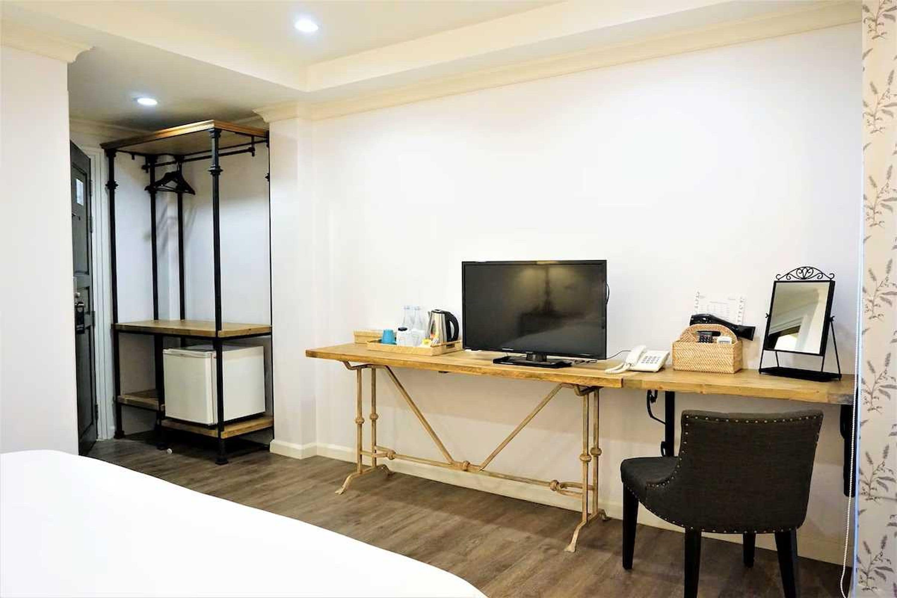 Une chambre avec un lit, un bureau avec un ordinateur, une chaise et une armoire.