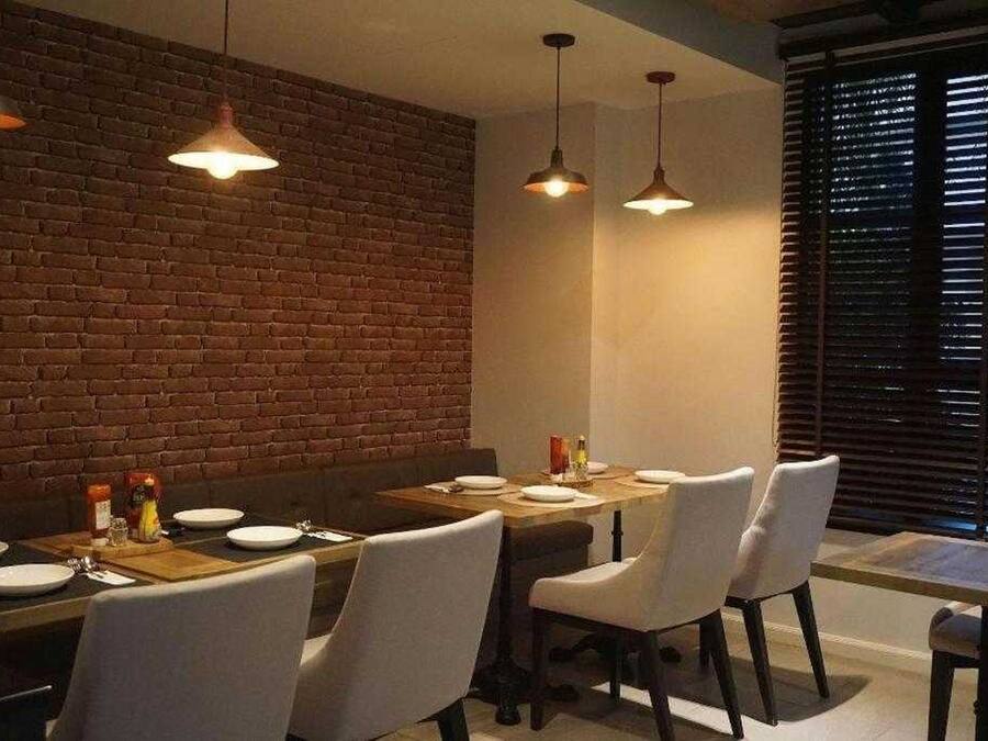 Comedor con pared de ladrillo, lámparas colgantes y mesa preparada para cuatro.