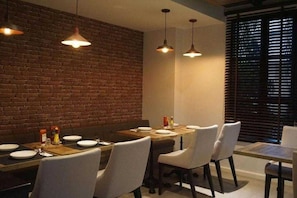 A dining area with a brick wall, pendant lights, and a table set for four. - Palette Marquise Boutique Hotel (Rayong)