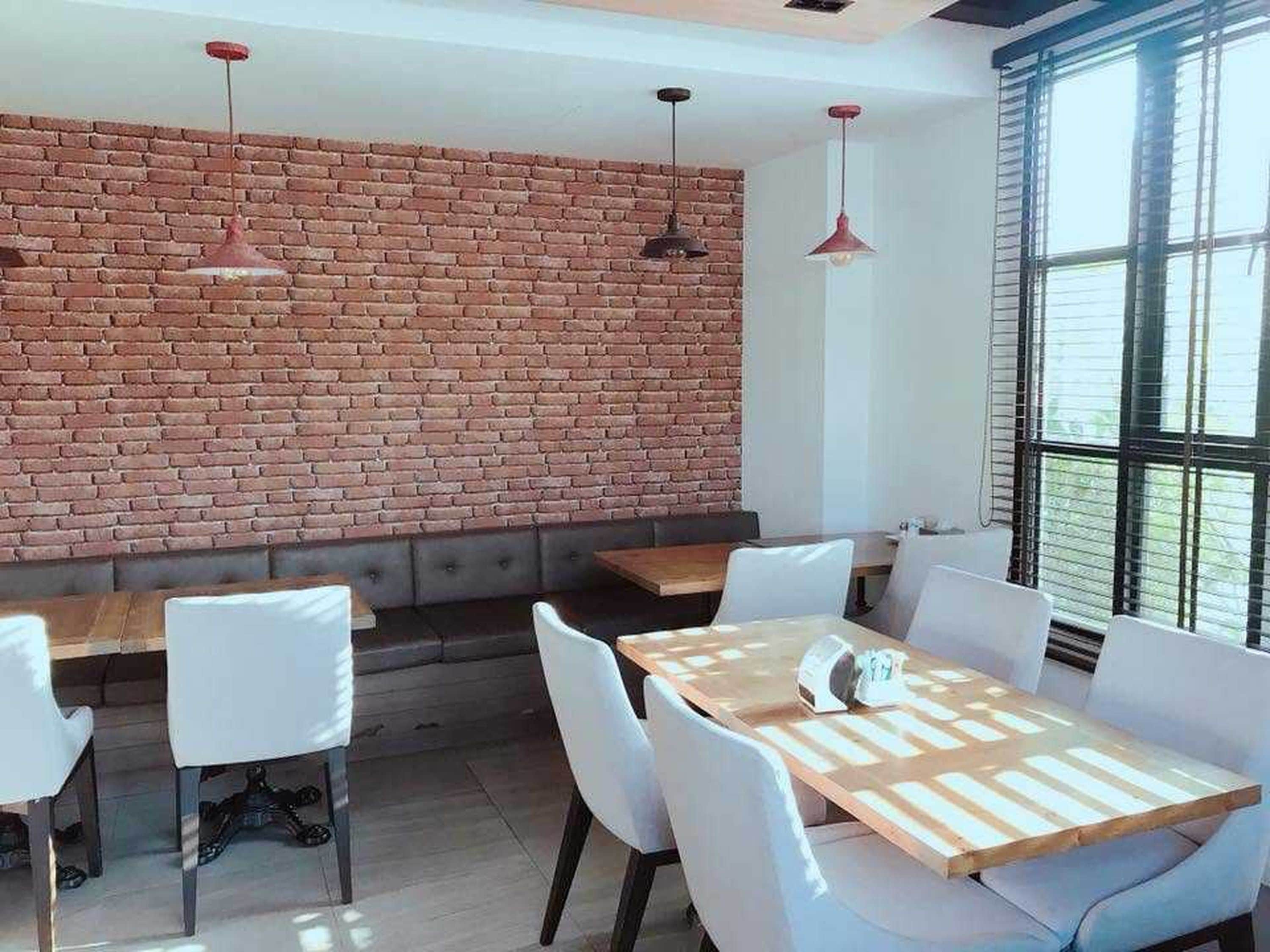 A modern interior with a brick wall, white furniture, and pendant lighting.