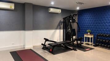 A gym with a bench press, dumbbells, and a blue wall.