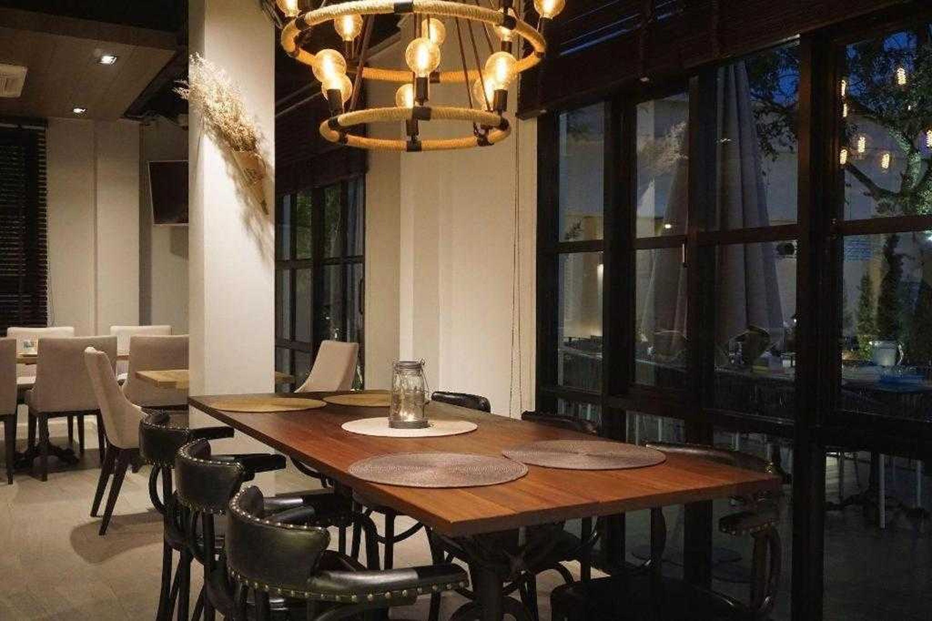 Un comedor con mesa de madera, sillas y lámpara colgante.