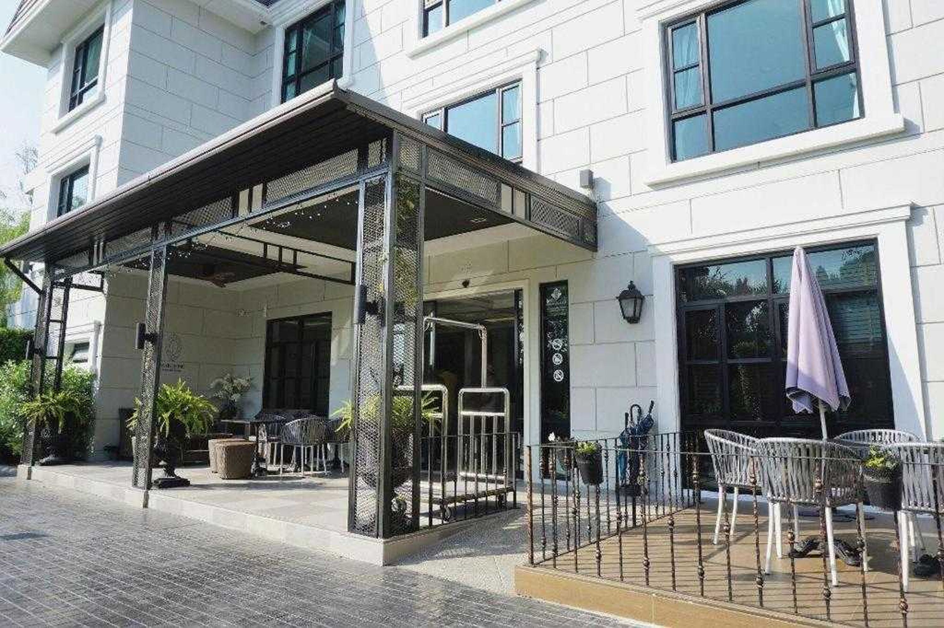 A hotel entrance with a covered outdoor area, a seating arrangement, and a gated entrance.