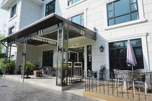 Entrada de hotel con zona exterior techada, disposición de asientos y acceso mediante portón.