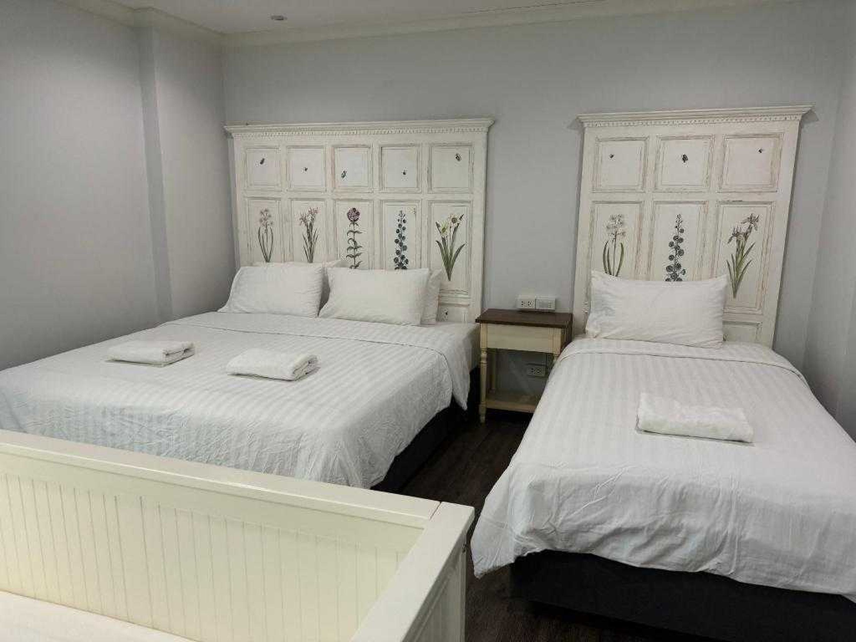Un dormitorio con dos camas, cada una con ropa de cama blanca y cabeceros decorativos.