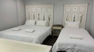 Un dormitorio con dos camas, cada una con ropa de cama blanca y cabeceros decorativos.