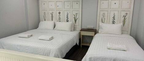 Una camera da letto con due letti, entrambi con lenzuola bianche e testiere decorative.