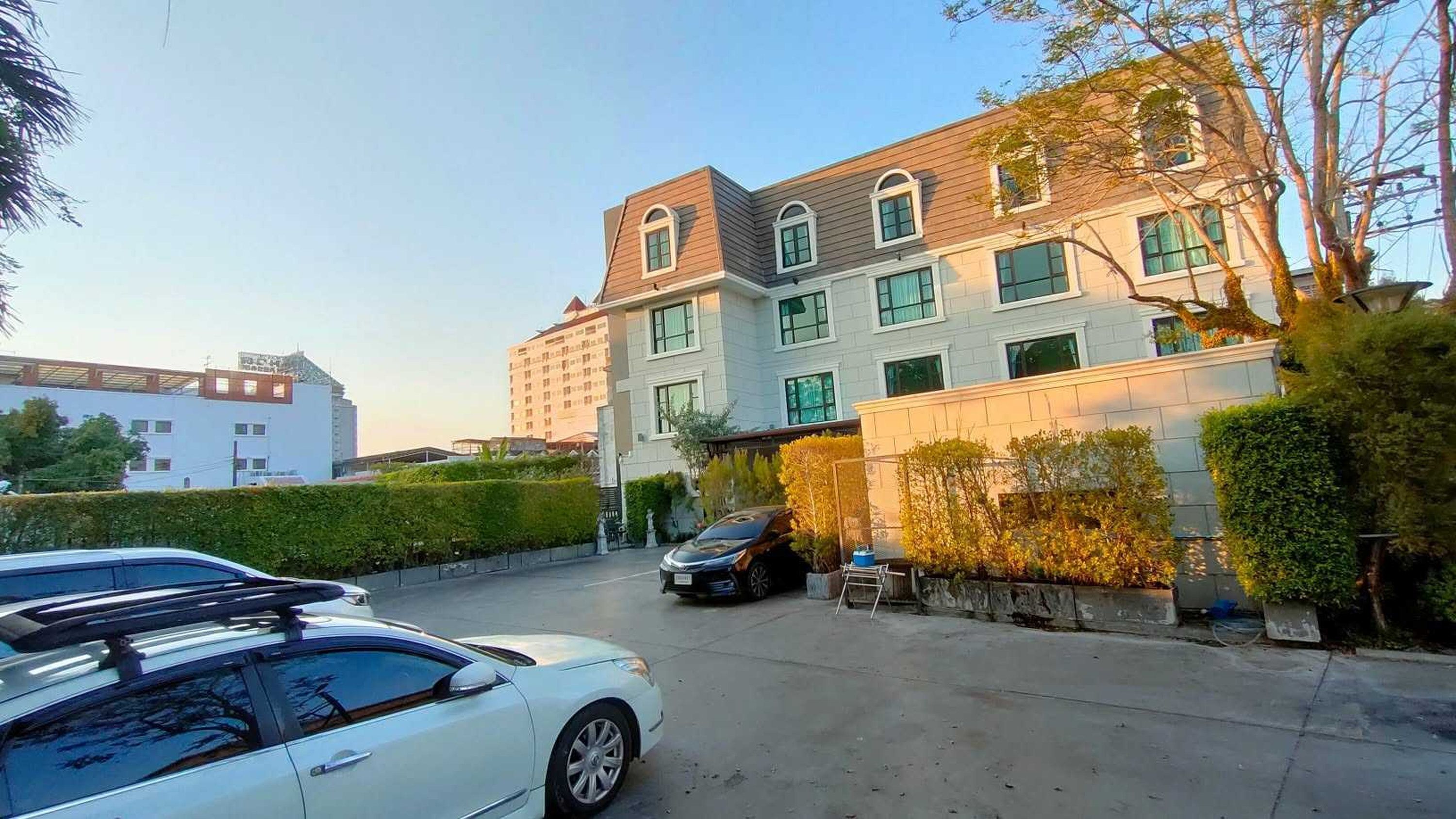 A multi-story building with a parking area in front.