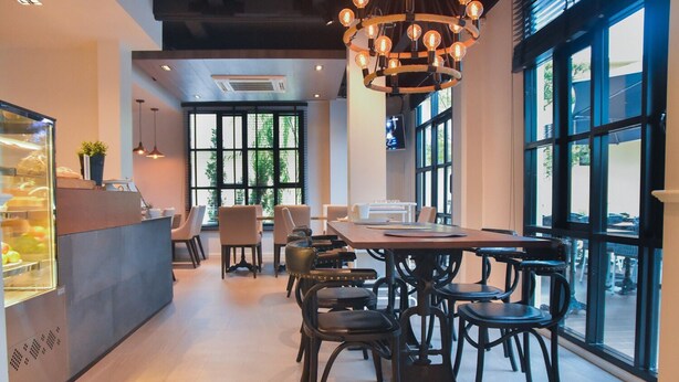 Un comedor moderno con una mesa central y sillas, ventanas amplias y una lámpara decorativa.