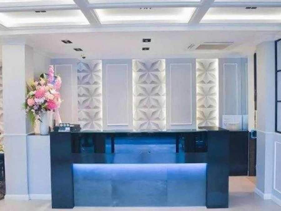 A reception area with a dark reception desk, white decorative panels, and a vase of flowers.