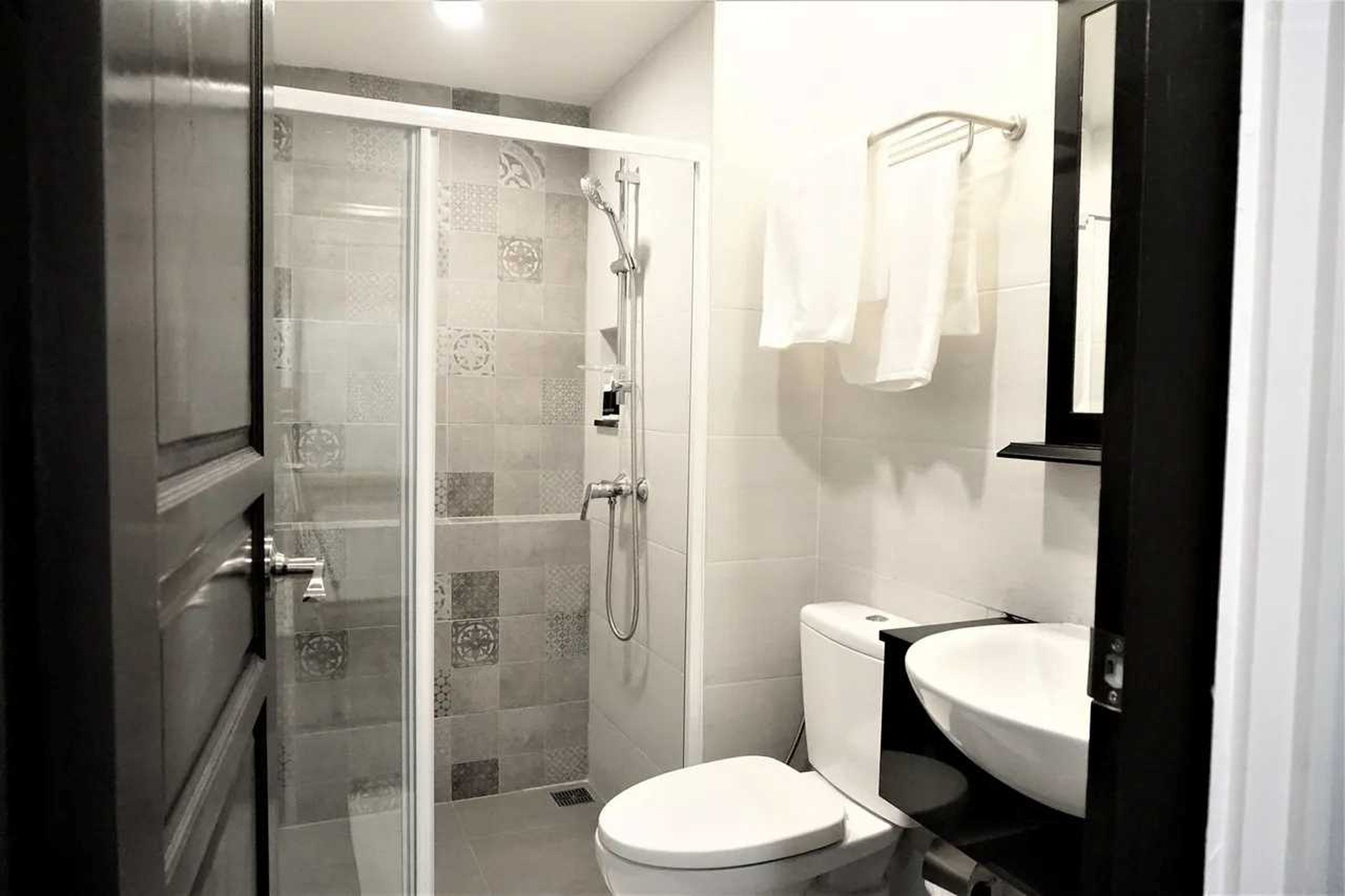 A bathroom with a glass-enclosed shower, a white toilet, and a sink with a mirror above it.