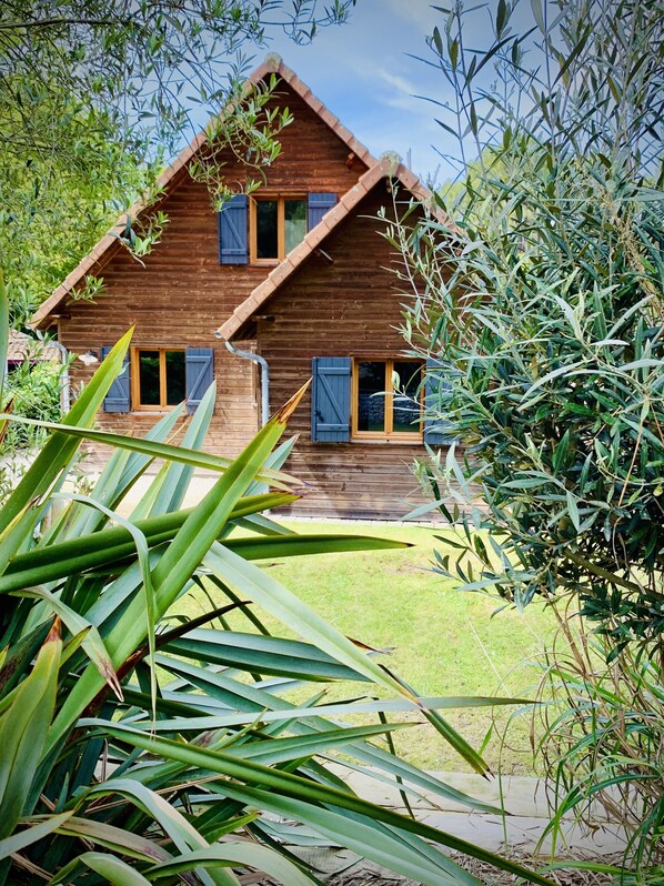A wooden house with a sloped roof and two visible windows with shutters. - Wooden family home Cap Ferret peninsula (Lège-Cap-Ferret)