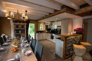 Een moderne keuken met witte kasten, een centraal eiland en een accentmuur van steen.