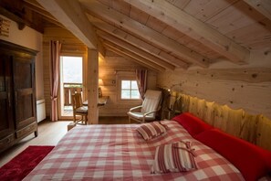 Een knus slaapkamer met houten wanden, een bed met ruitjesdessin, een rode bank en een houten plafond.