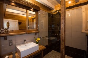 Een moderne badkamer met een houten wastafelmeubel, een grote spiegel en een douche met glazen wanden.