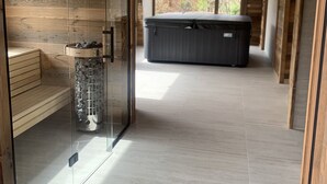 Un espace spa moderne doté d’un sauna à parois de verre, d’un banc en bois et d’un jacuzzi.