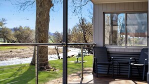 A balcony with a view of a park, a bench, and a table.