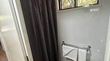 Un baño pequeño con cortina de ducha, inodoro y barra para toallas.