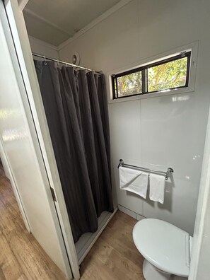 A compact bathroom with a shower curtain, a toilet, and a towel rack.