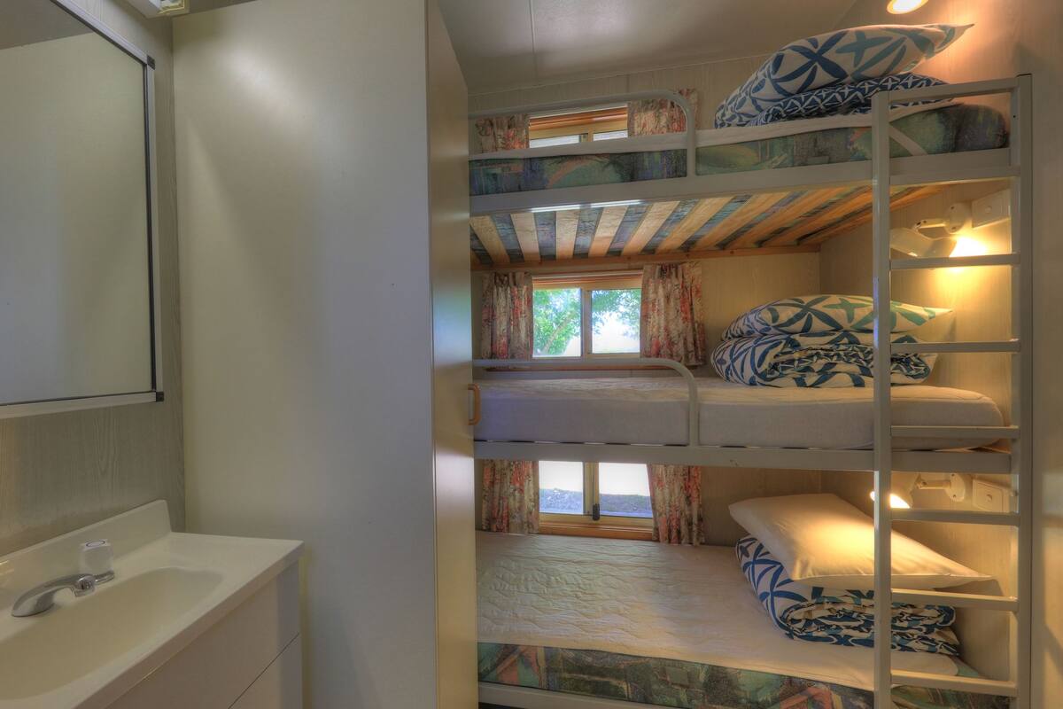 A bunk bed room with a bathroom including a sink and mirror.