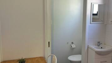 Un baño pequeño y limpio con inodoro, lavamanos y espejo.