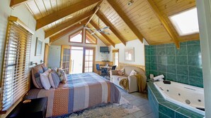 Un dormitorio amplio con una cama grande, un rincón de descanso con un sofá, un escritorio y un baño con bañera.