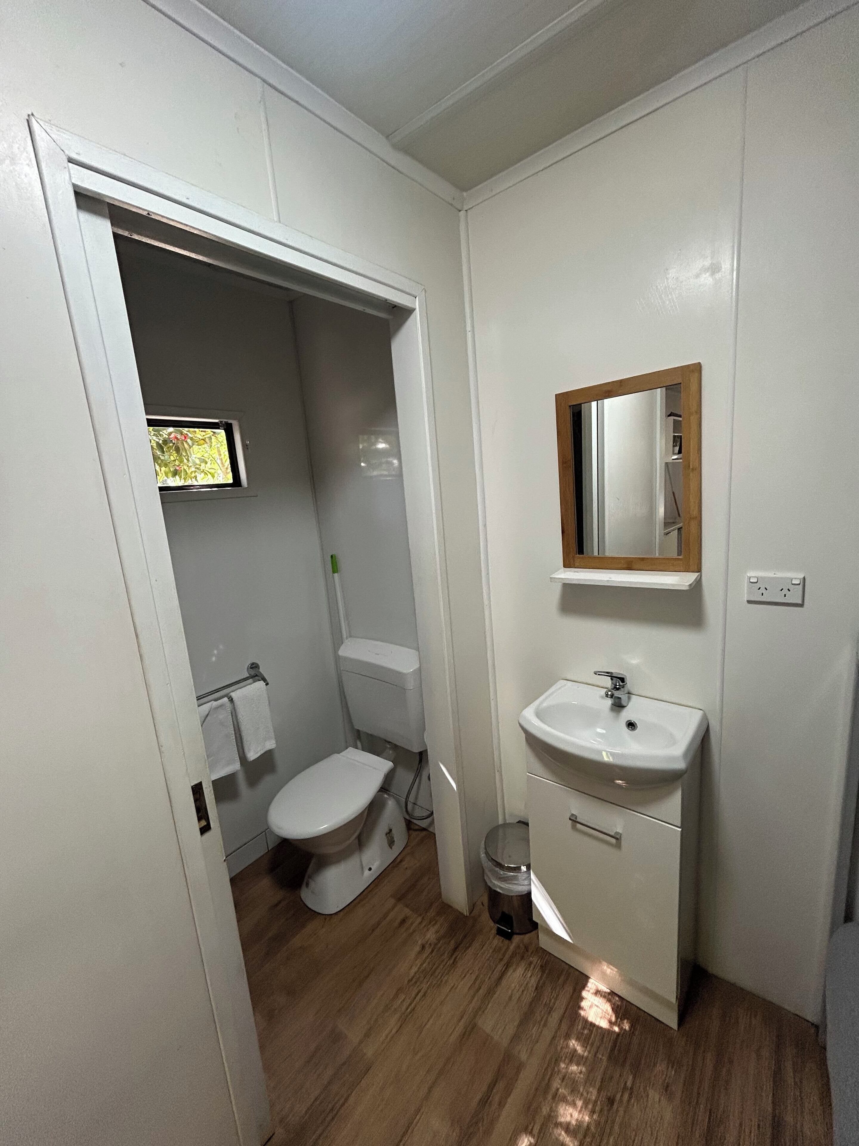 Pieni, käytännöllinen kylpyhuone, jossa on wc, pesuallas ja peili.