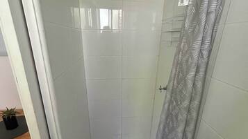 A small, enclosed shower area with a showerhead, a drain, and a shower curtain.