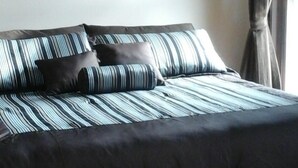 Ein Schlafzimmer mit einem Bett, einem Gemälde und einem Fenster mit Vorhängen.