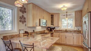 Eine Küche mit Holzausstattung, Granit Arbeitsplatten, einer integrierten Mikrowelle und einem Kühlschrank.