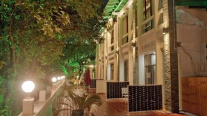 A corridor with a wooden floor, a railing, and a building with multiple windows and a green roof. - Guilin Crystal Crescent Moon Hotel (Guilin)