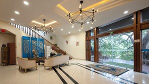 A lobby with a staircase, a reception desk, and a large window with a view of trees. - Guilin Crystal Crescent Moon Hotel (Guilin)