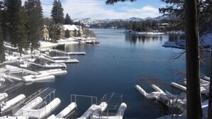 A marina with boats docked, surrounded by snow-covered trees and mountains in the background.