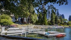 A marina with docked boats, a dock structure, and a backdrop of trees and buildings.
