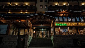 A hotel entrance with a staircase leading up to a covered area adorned with string lights. - Armon Greenblu Hotel & Wellness (Dimaro Folgarida)