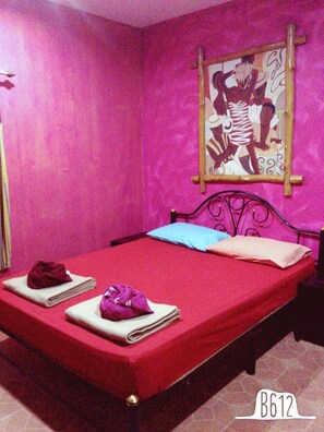 A room with a bed, pillows, and towels.