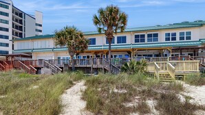 A beachfront building with a covered walkway and a palm tree.