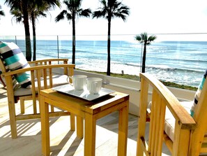 Enjoy the tranquil ocean views from this balcony, featuring a table for two and a comfortable chair.