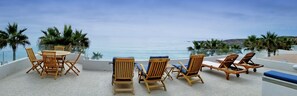 Relax in style with ocean views from this serene seating area, featuring comfortable lounge chairs and a small table.