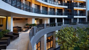 A multi-level atrium with a curved glass railing, seating areas, and a view of the surrounding greenery. - Seven Doors in Gramercy Makati (Makati)