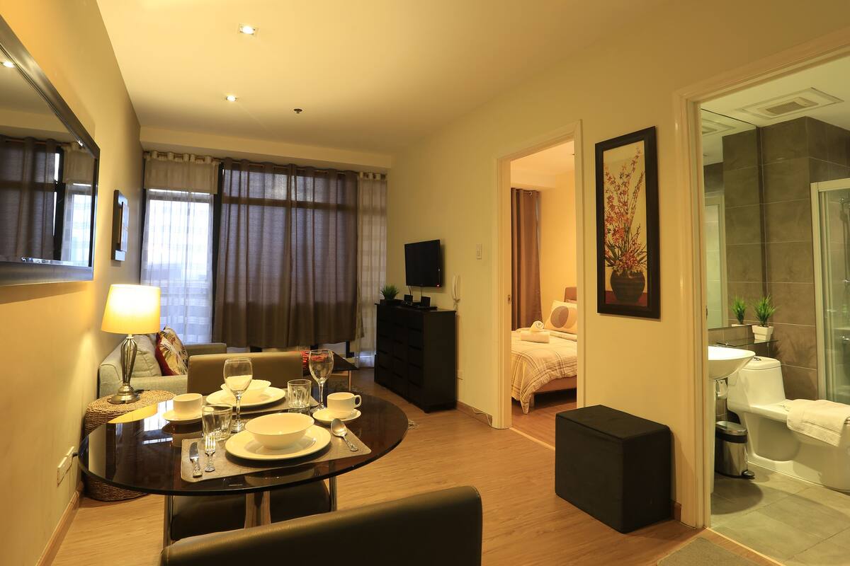A hotel room with a dining area, a bed, a bathroom, and a TV.