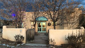 A building with a stone pathway leading to a door, surrounded by bare trees and a stone wall.
