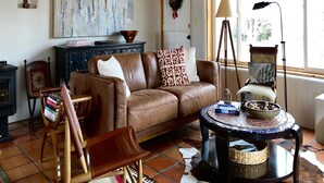 A cozy living room with a brown leather sofa, a wooden coffee table, and a rustic fireplace.