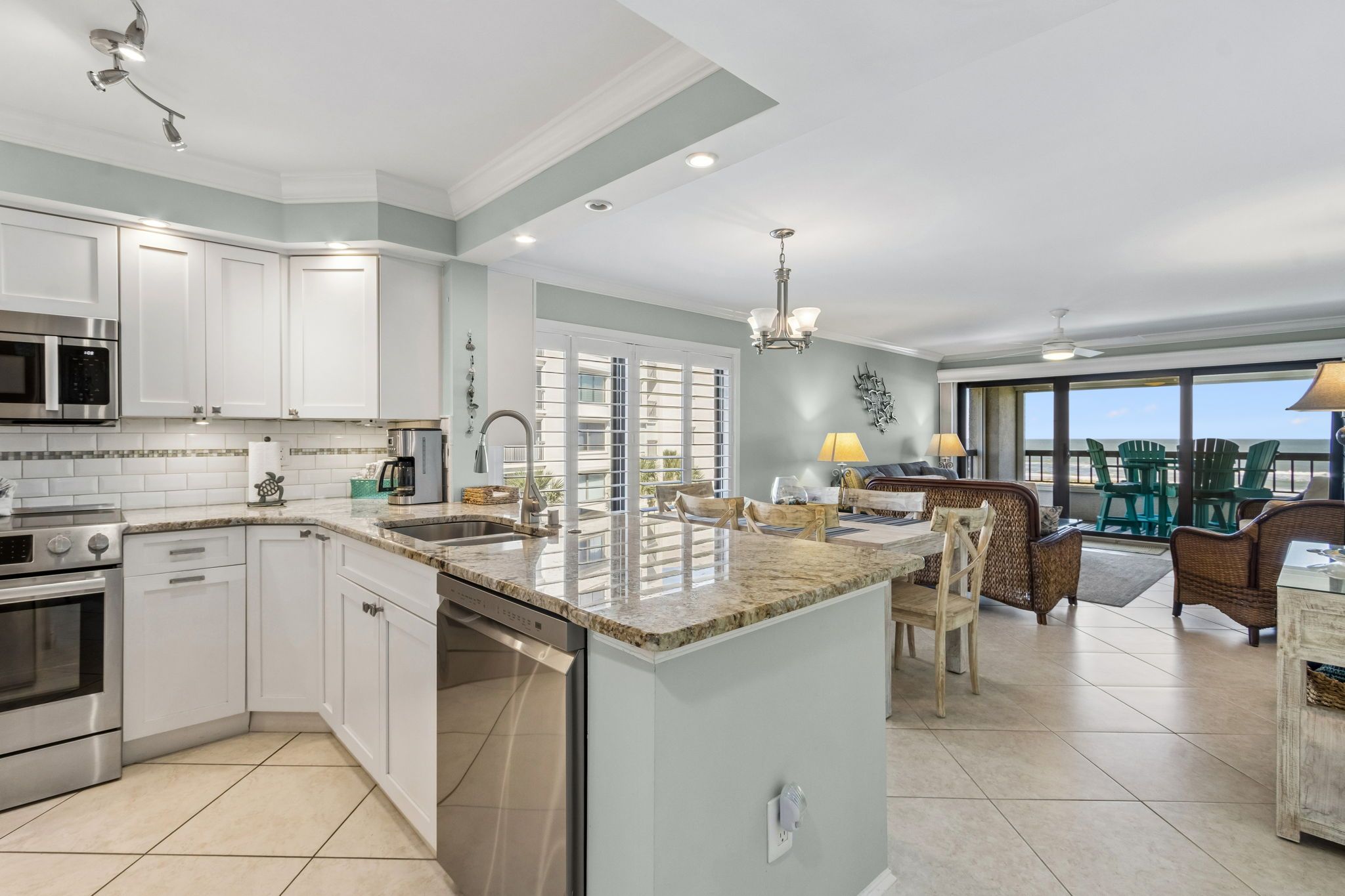 A modern kitchen with stainless steel appliances, a large island, and a dining area with a view of the ocean.