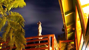 A staircase leading to a wooden deck with a statue on top, surrounded by greenery. - 8 minutes to Nat'l Park! Enjoy the sound of rain & birds in a peaceful retreat. (Volcano)