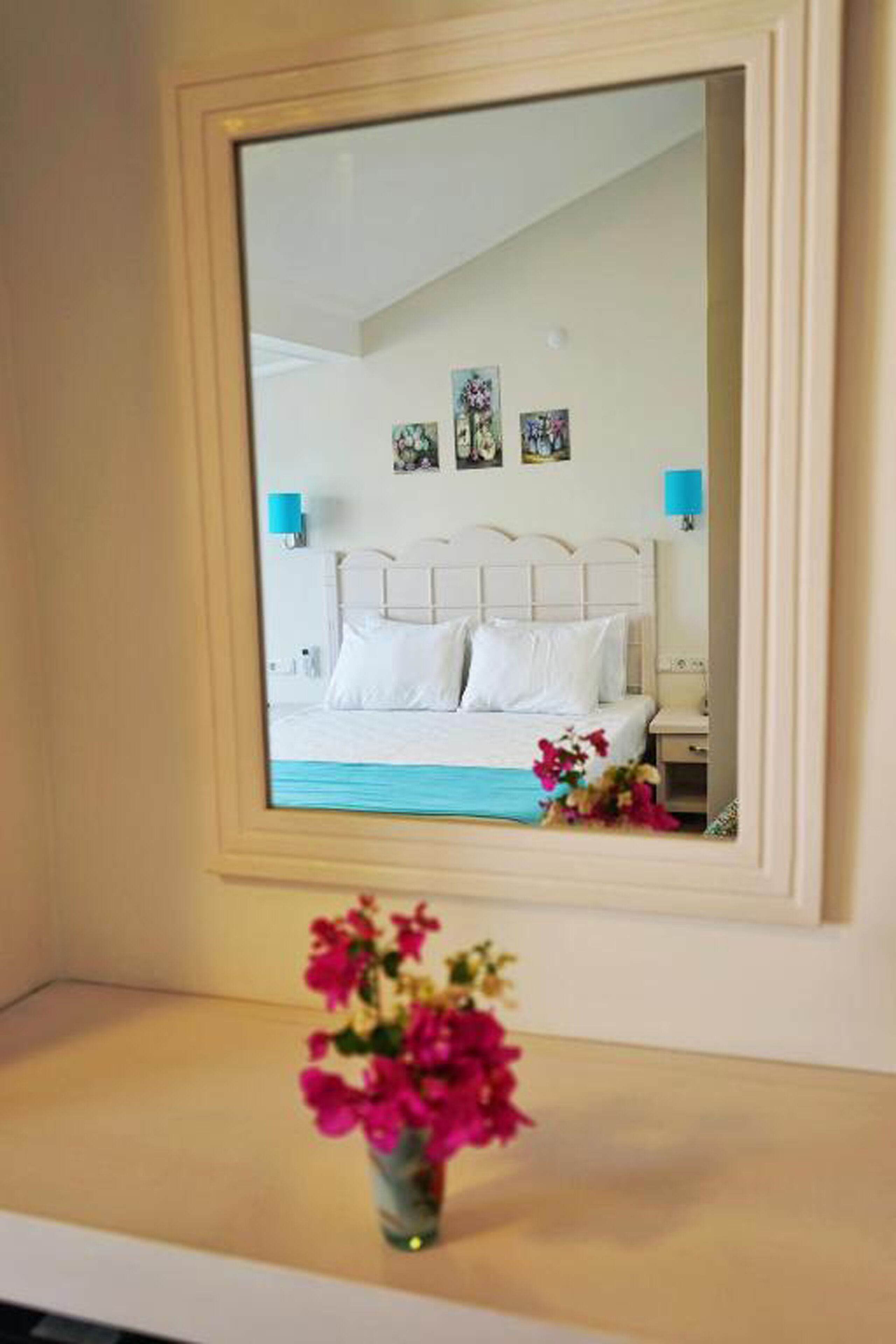 Un dormitorio con una cama, una mesita de noche, una lámpara y un florero con flores.