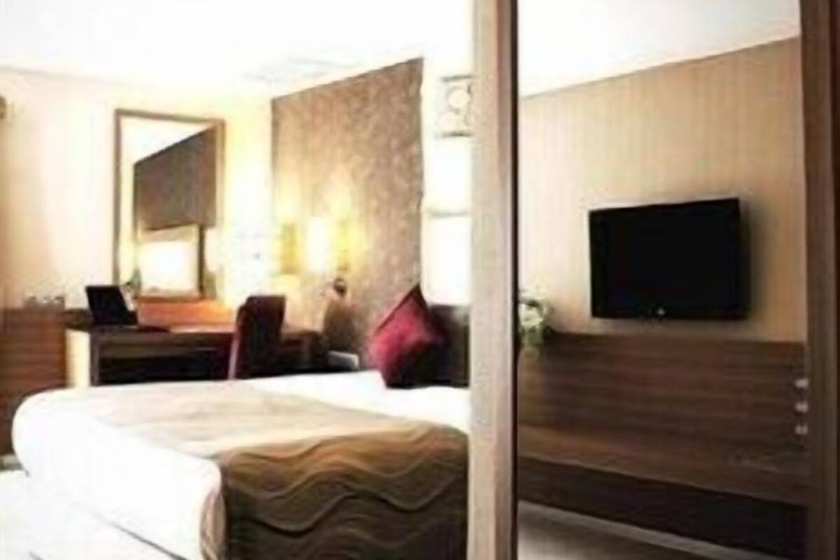 Una camera d'albergo con un letto, una scrivania, una sedia, una televisione e uno specchio.